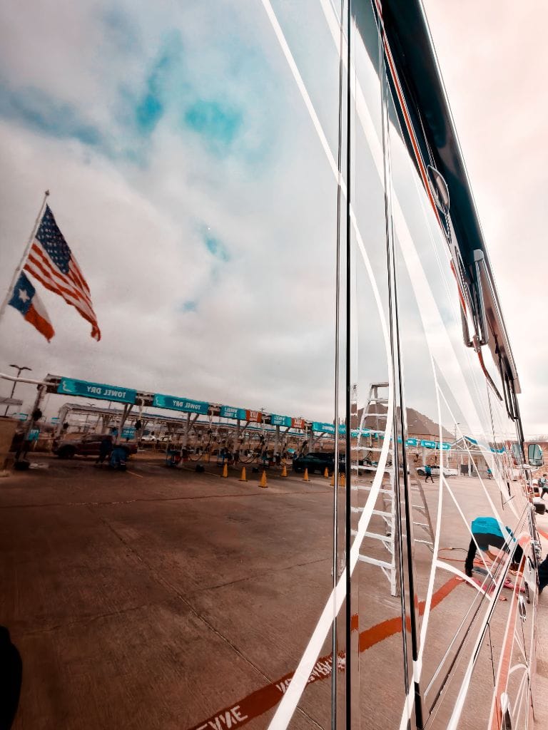 Mirror-perfect shine on a large coach bus being detailed at Brightworks Fort Worth — facility reflected in the paint