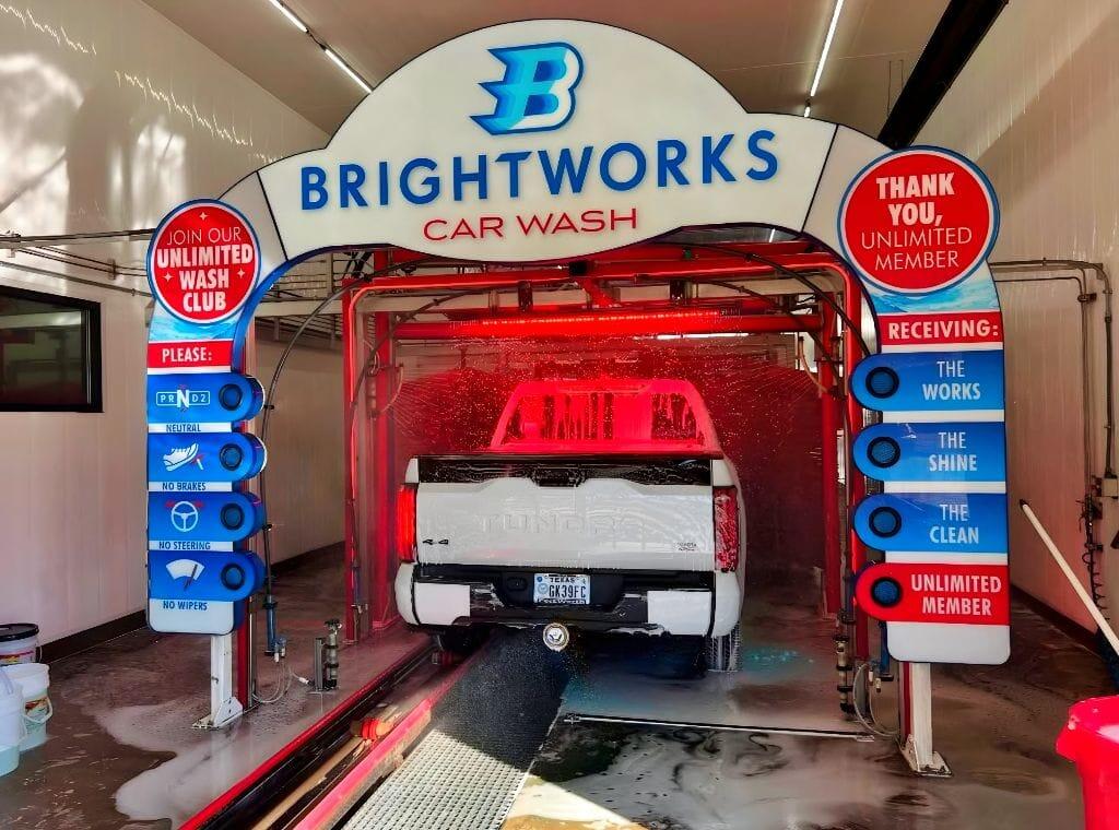 White Toyota Tundra entering the Brightworks Car Wash exterior wash under the illuminated branded entry arch