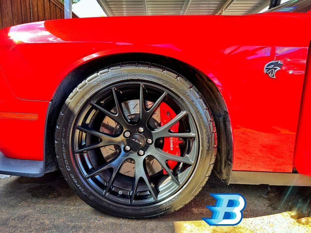 Red Dodge Challenger Hellcat wheel and Brembo brake caliper detail at Brightworks Granbury — Brightworks logo watermark